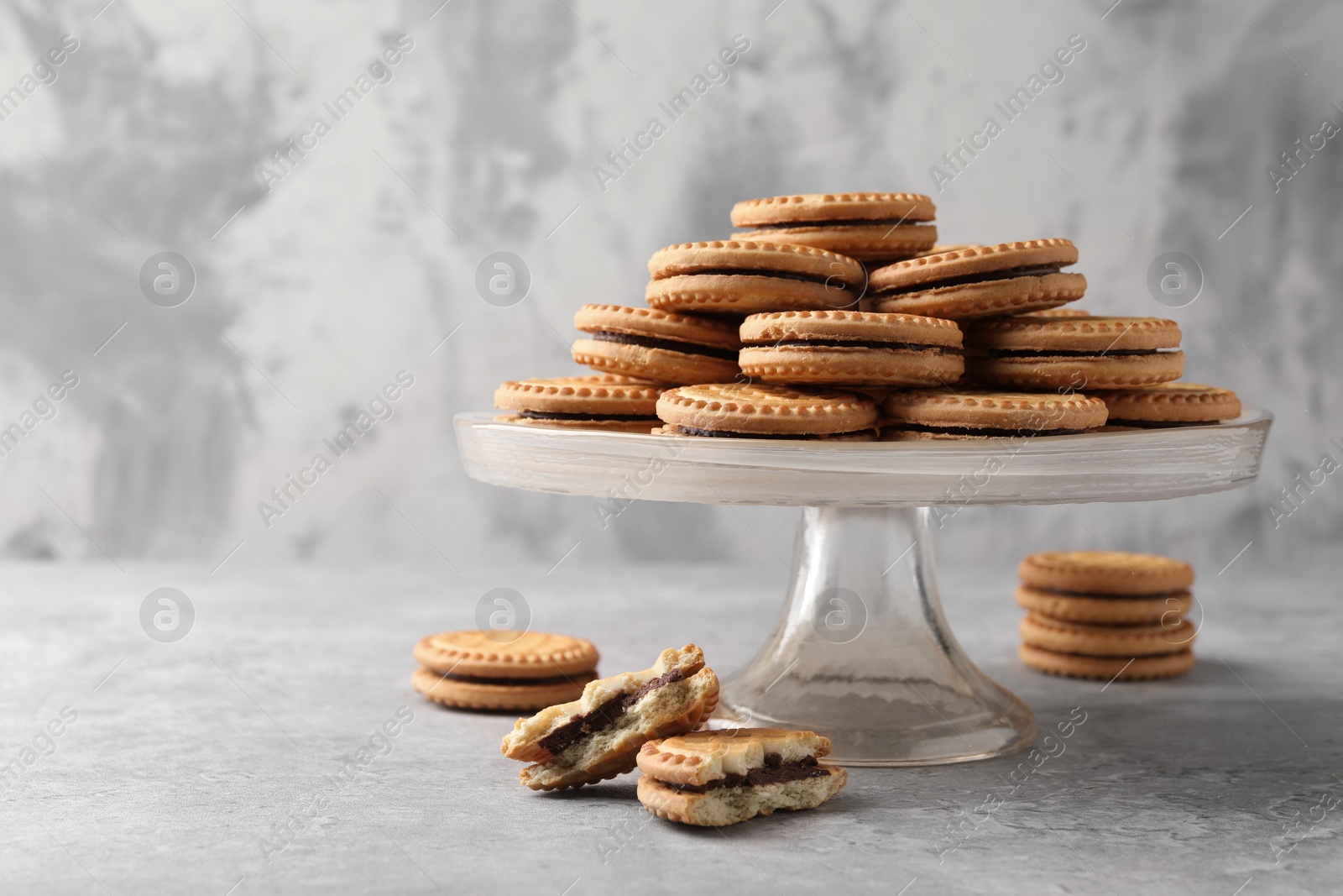 Photo of Tasty sandwich cookies with cream on grey table. Space for text