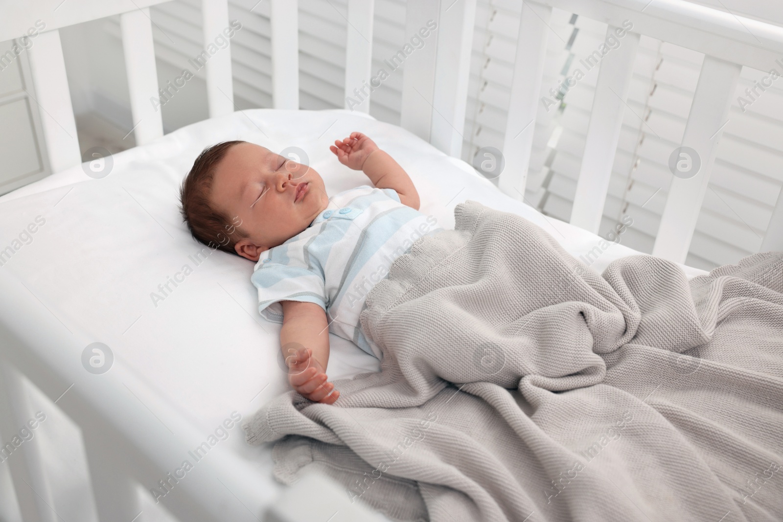 Photo of Cute newborn baby sleeping under blanket in crib. Bedtime