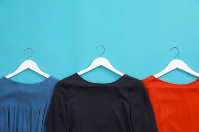 Photo of Collection of women's garments on light blue background, flat lay with space for text. Clothes rent concept