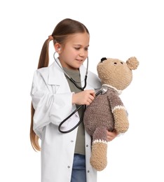 Photo of Little girl playing doctor with toy bear on white background