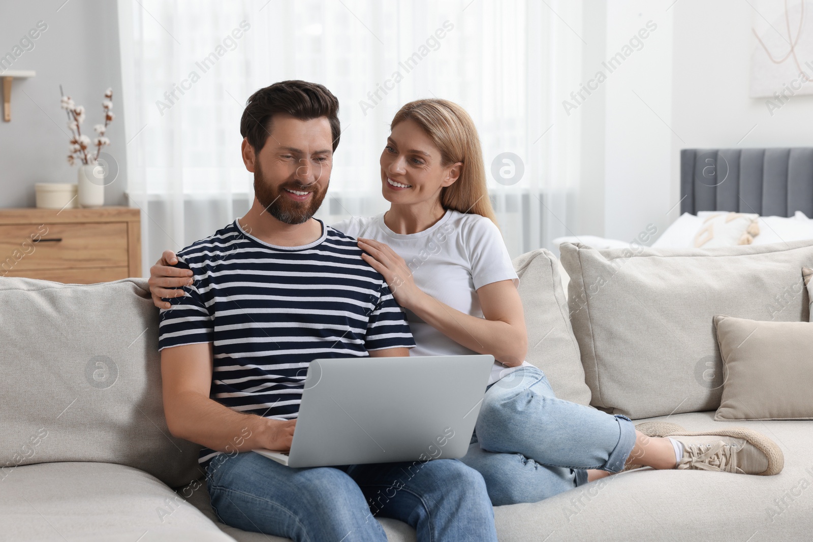 Photo of Happy couple with laptop on sofa at home