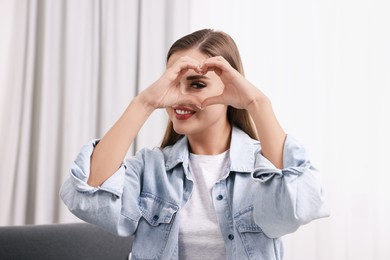 Photo of Happy woman showing heart gesture with hands indoors