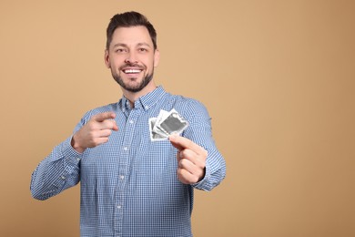 Photo of Happy man holding condoms on beige background. Space for text