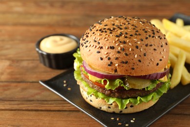 Photo of Burger with delicious patty, french fries and sauce on wooden table, closeup