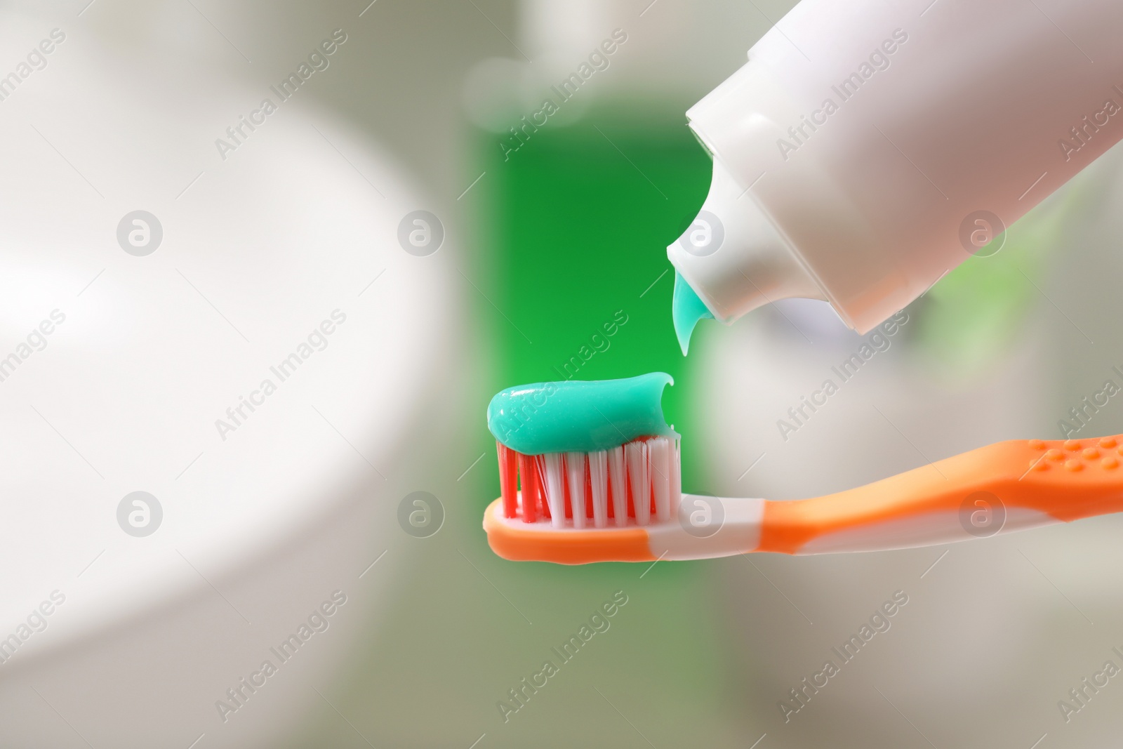 Photo of Applying toothpaste on brush against blurred background, closeup