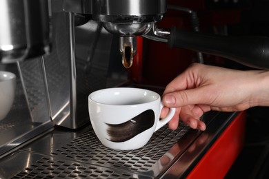 Photo of Barista making aromatic espresso using professional coffee machine in cafe, closeup