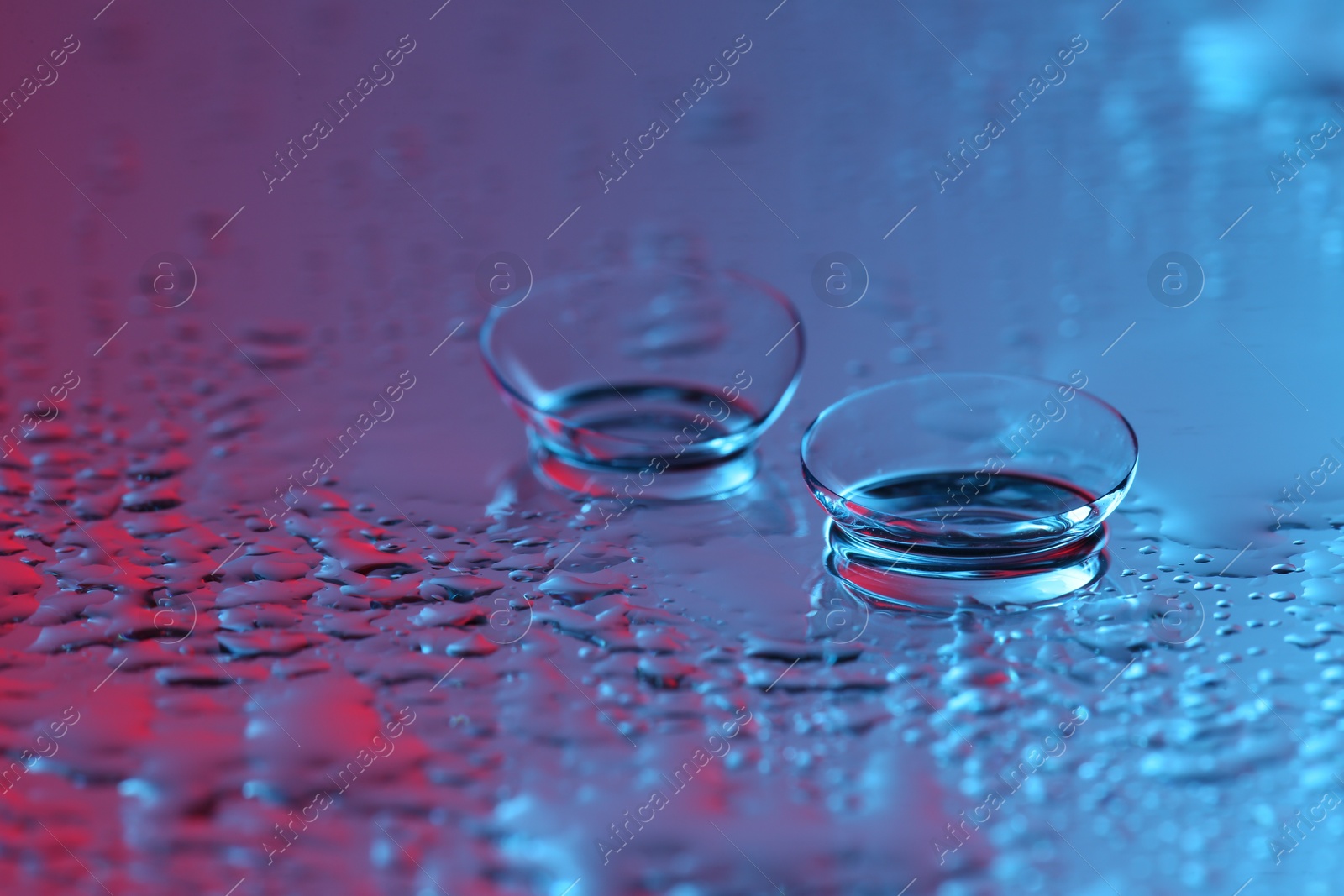 Photo of Pair of contact lenses on wet mirror surface. Space for text