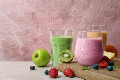 Photo of Glasses with healthy detox smoothies and ingredients on table