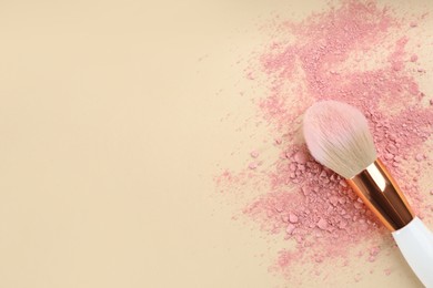 Photo of Makeup brush and scattered blush on beige background, top view. Space for text