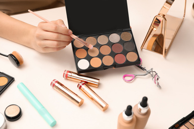 Photo of Beauty blogger with brush and eyeshadow palette at table, closeup