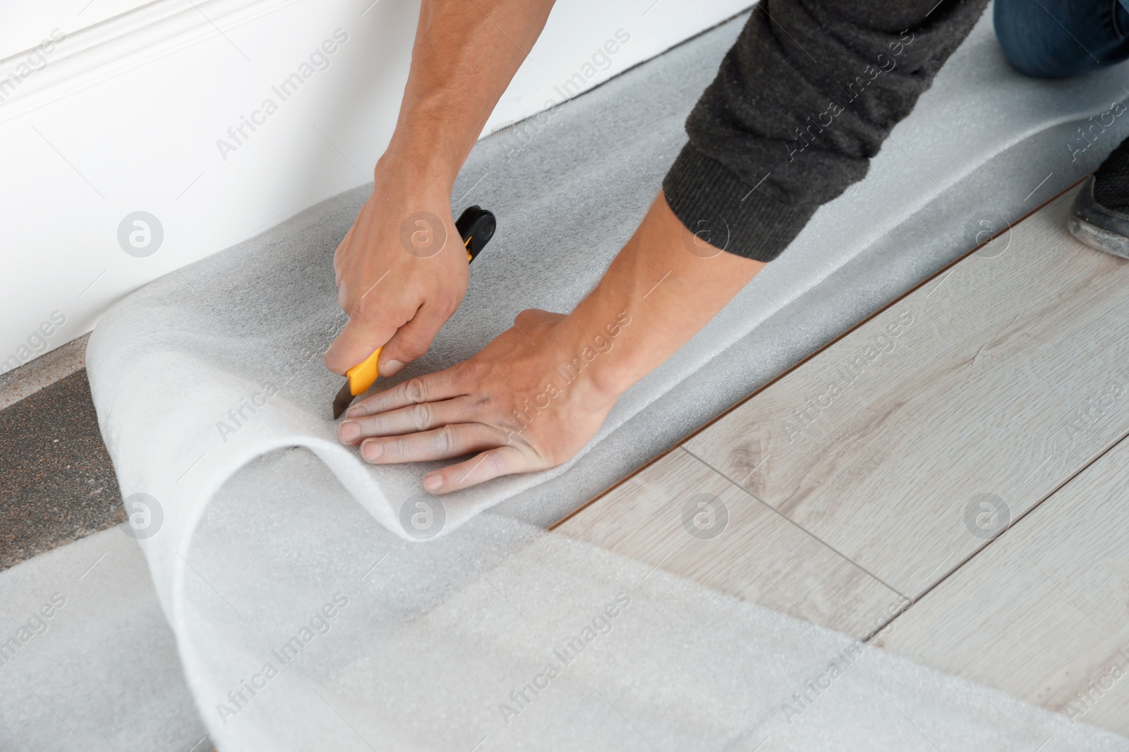 Photo of Worker installing new laminate flooring in room, closeup