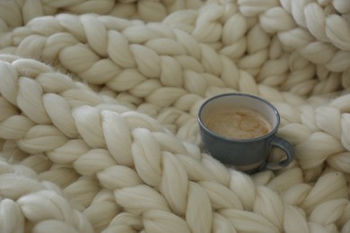 Cup of coffee on white knitted plaid. Space for text