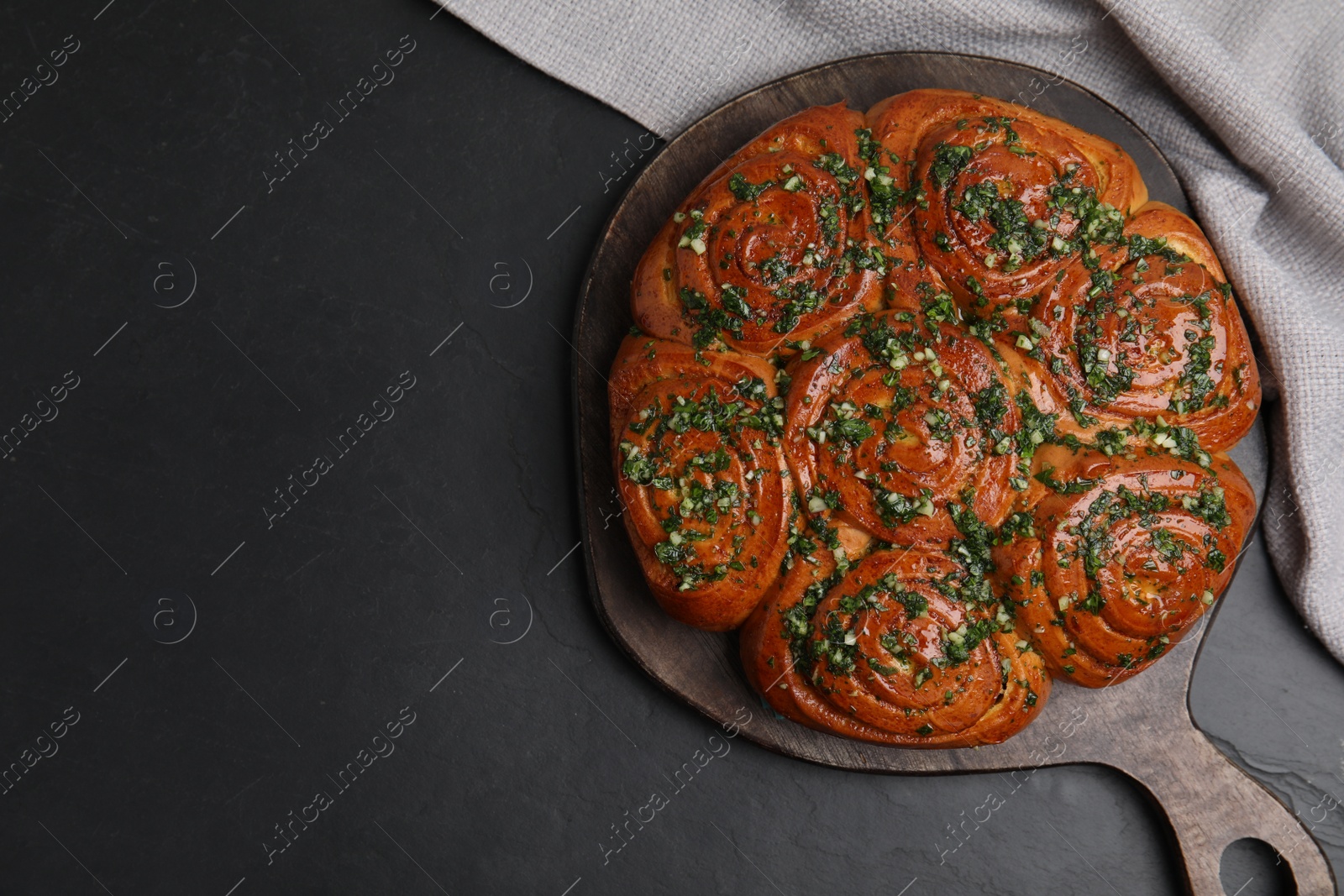 Photo of Traditional Ukrainian garlic bread with herbs (Pampushky) on black table, flat lay. Space for text