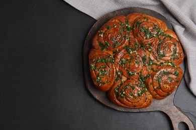 Traditional Ukrainian garlic bread with herbs (Pampushky) on black table, flat lay. Space for text