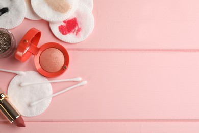 Photo of Dirty cotton pads, swabs and cosmetic products on pink wooden background, flat lay. Space for text