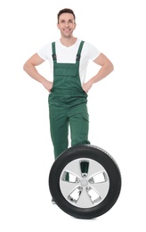 Photo of Young mechanic in uniform with car tire on white background