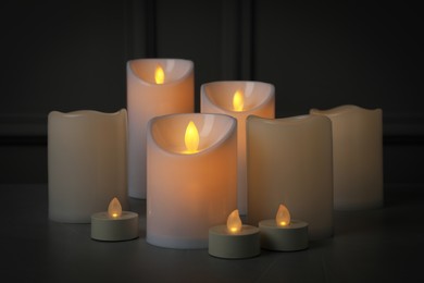Photo of Glowing decorative LED candles on grey table