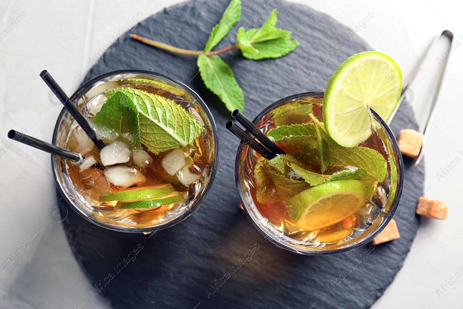 Photo of Glasses with delicious mint julep cocktail on slate plate, top view