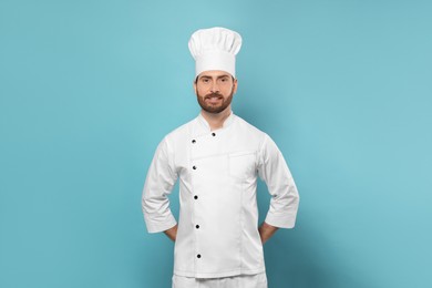 Photo of Smiling mature chef on light blue background