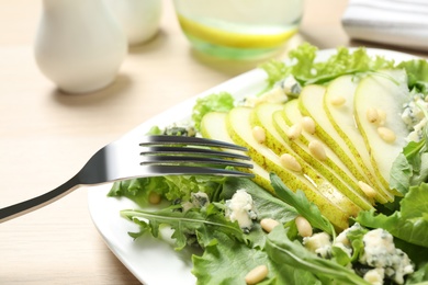 Photo of Fresh salad with pear served on wooden table