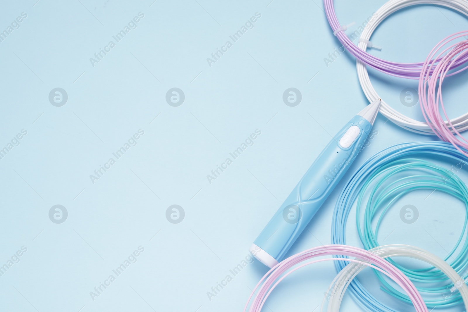 Photo of Stylish 3D pen and colorful plastic filaments on light blue background, flat lay. Space for text