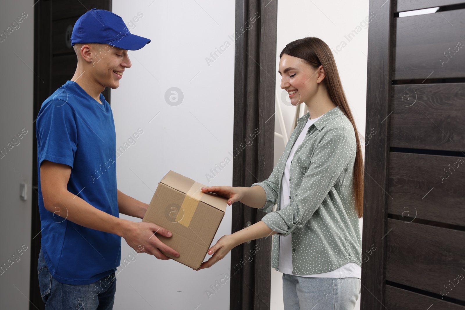 Photo of Happy courier giving parcel to receiver indoors