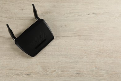 Photo of Modern Wi-Fi router on wooden background, top view. Space for text