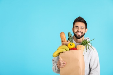 Photo of Man holding paper bag with fresh products on color background, space for text. Food delivery service