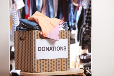 Photo of Donation box with clothes on table indoors