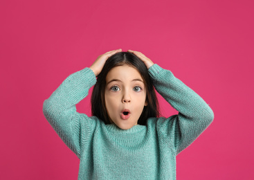 Portrait of cute little girl on pink background