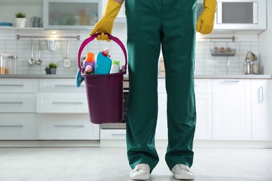 Photo of Janitor with bucketdetergents in kitchen, closeup. Cleaning service