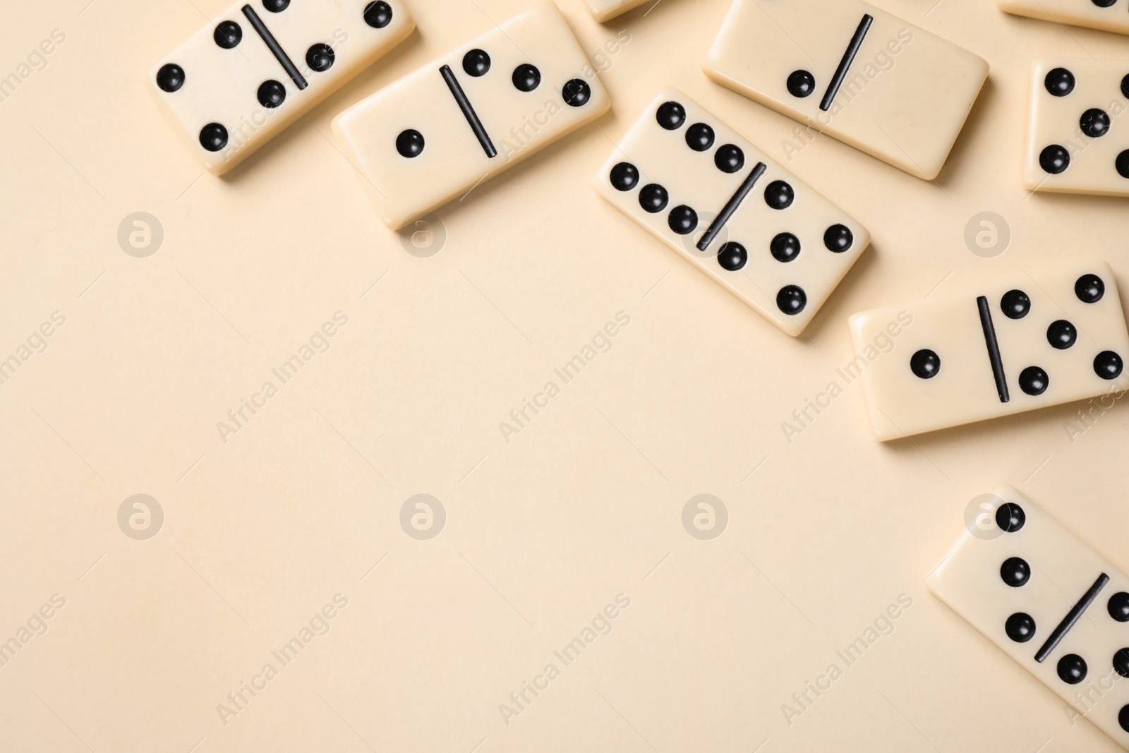 Photo of Classic domino tiles on beige background, flat lay. Space for text