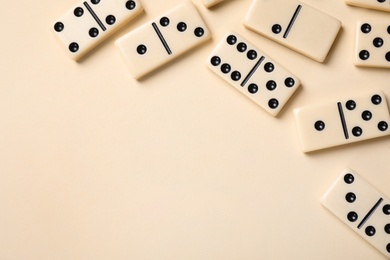 Classic domino tiles on beige background, flat lay. Space for text