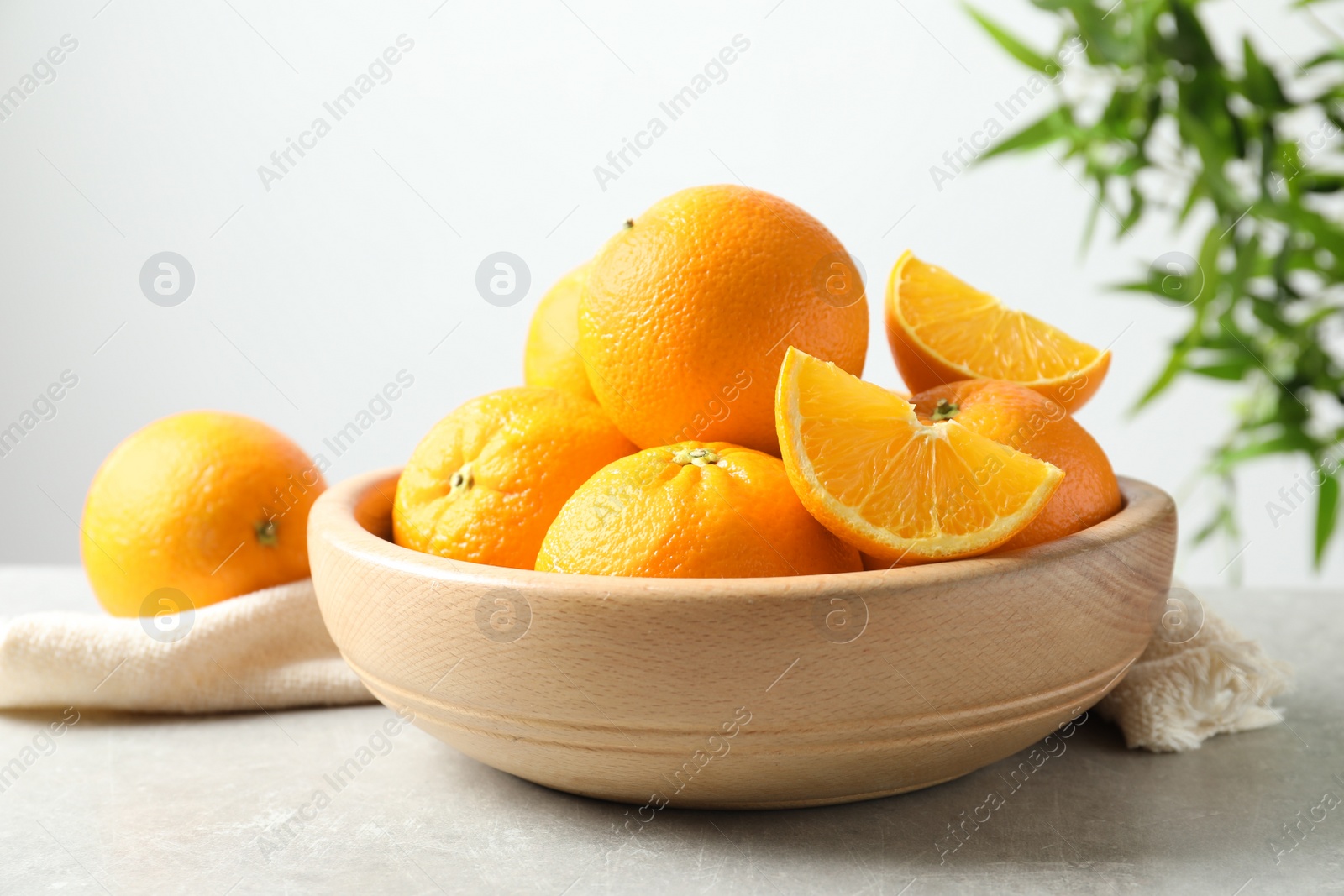 Photo of Bowl with ripe oranges on table against blurred background