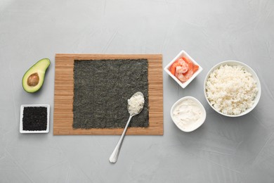Photo of Cooking sushi. Nori, spoon with rice and other ingredients on grey textured table, flat lay