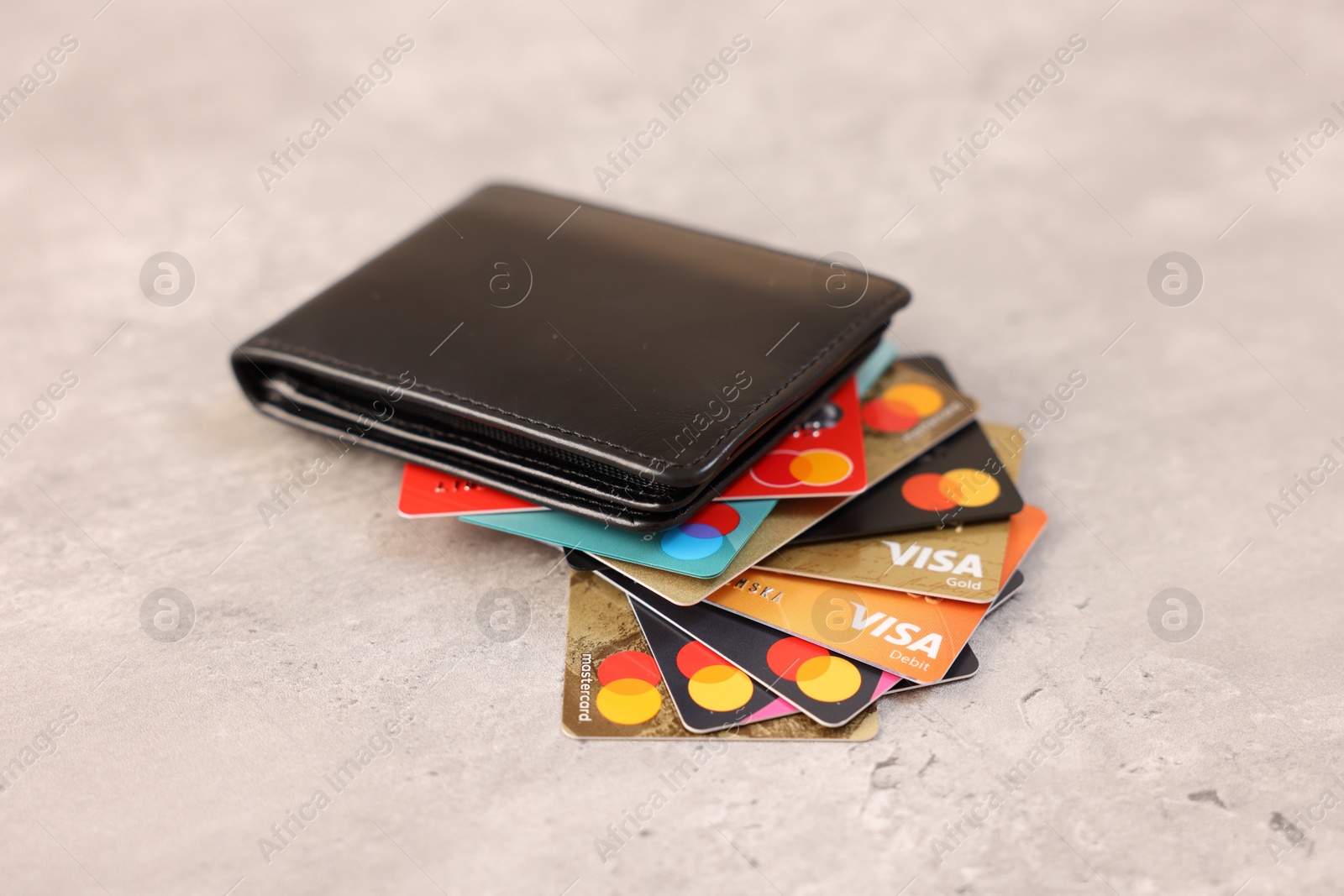 Photo of LEIDEN, NETHERLANDS - MARCH 07, 2024: Bank cards of Visa and Mastercard payment systems in leather wallet on light grey table