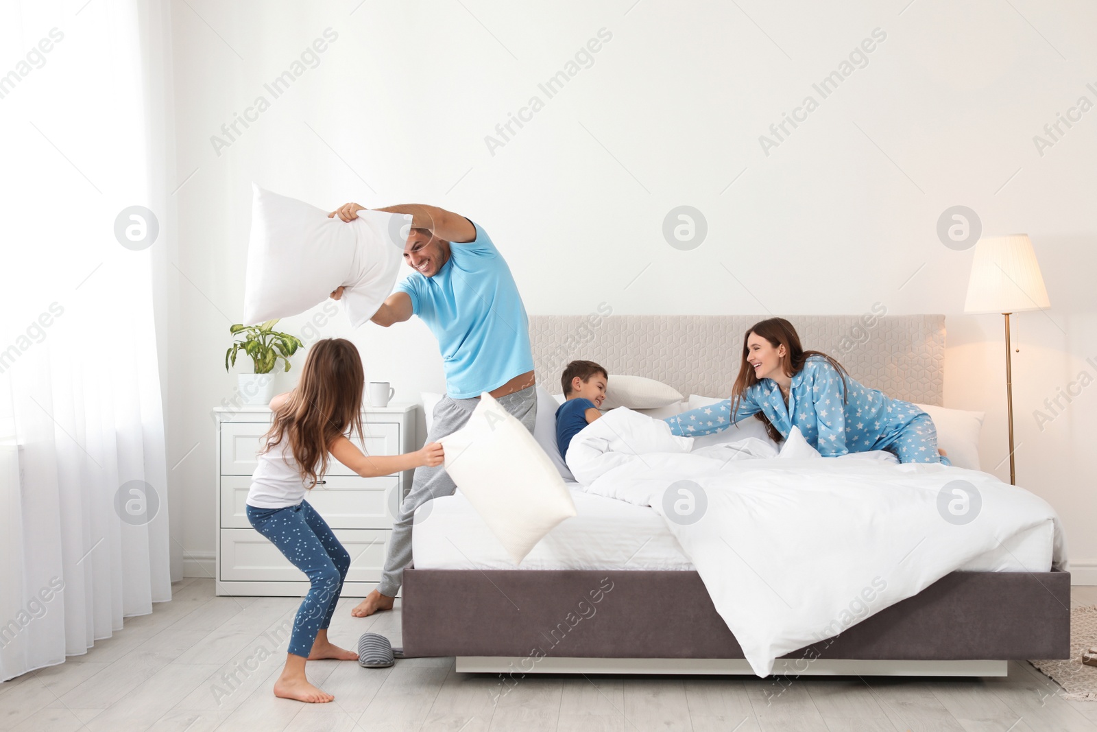 Photo of Happy family having pillow fight in bedroom