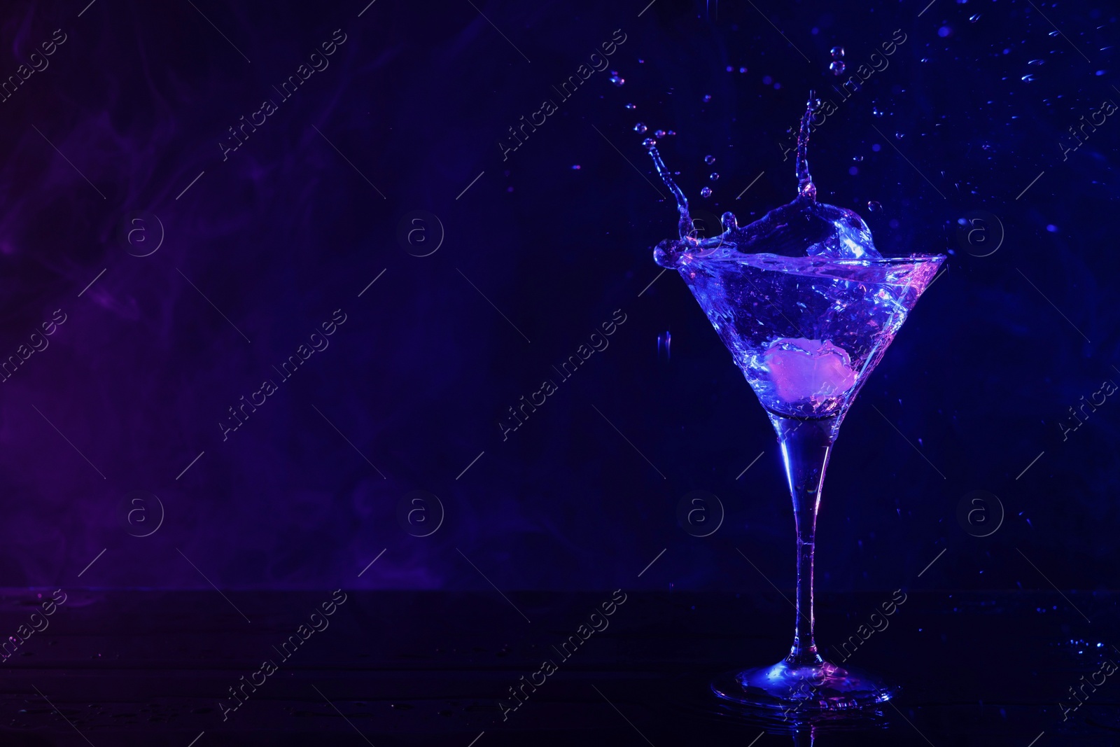 Photo of Martini splashing out of glass in neon lights, space for text