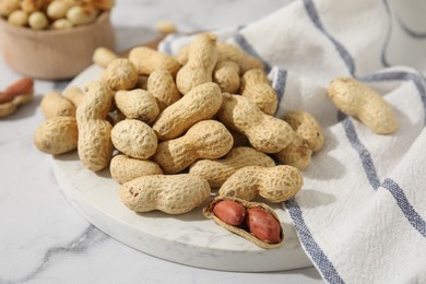 Fresh unpeeled peanuts on white marble table, closeup