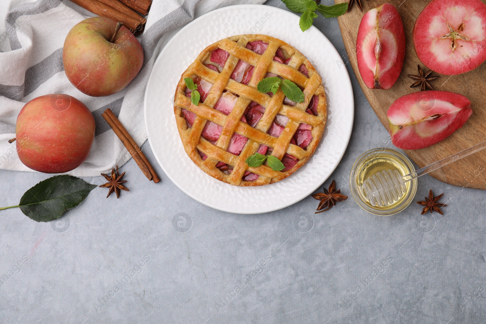 Photo of Delicious apple pie with mint and ingredients on grey table, flat lay. Space for text