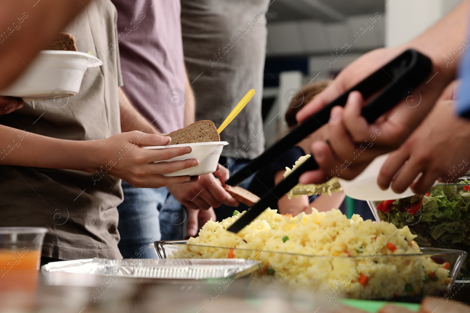 Photo of Volunteer serving food to poor people in charity centre, closeup