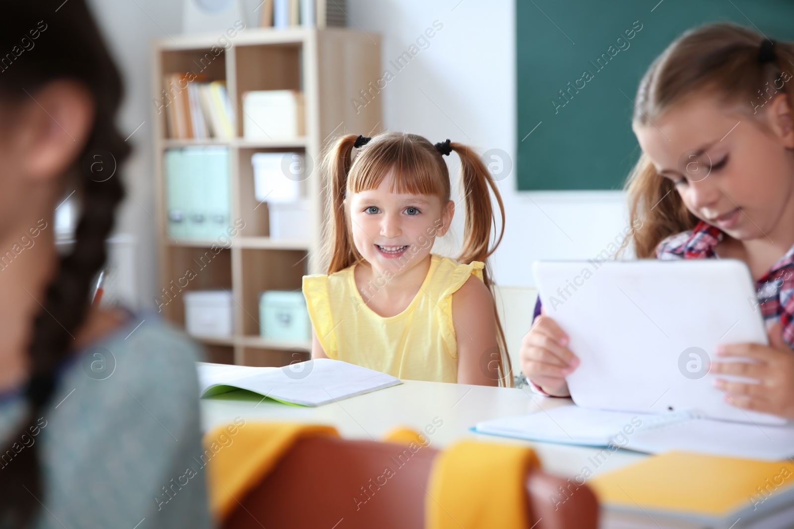 Photo of Cute little child sitting at desk in classroom. Elementary school