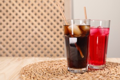 Photo of Glasses of different refreshing soda water with ice cubes and straws on wooden table, space for text