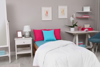 Photo of Modern teenager's room interior with comfortable bed and workplace