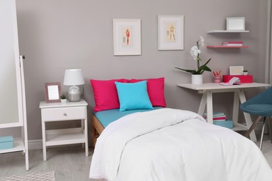 Modern teenager's room interior with comfortable bed and workplace