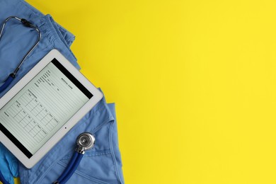 Photo of Medical uniform, tablet and stethoscope on yellow background, flat lay. Space for text