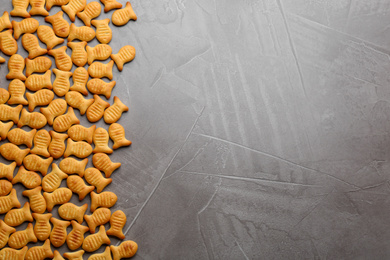 Photo of Delicious goldfish crackers on grey table, flat lay. Space for text