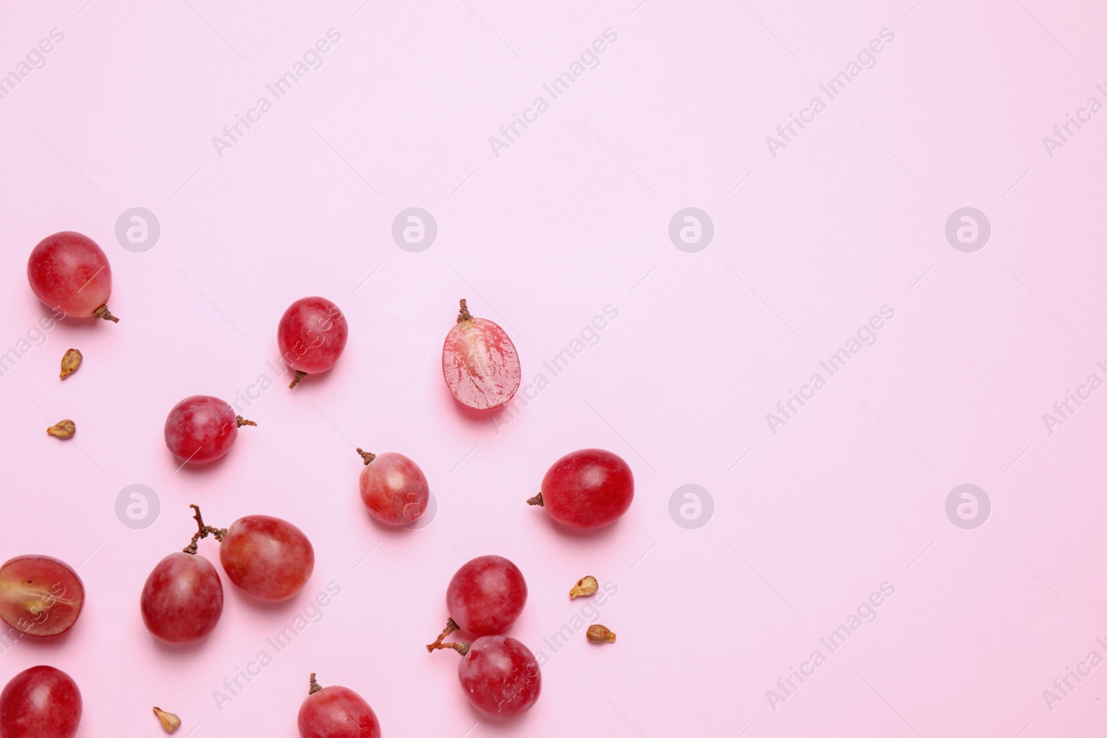 Photo of Flat lay composition with fresh ripe grapes and seeds on pink background. Space for text