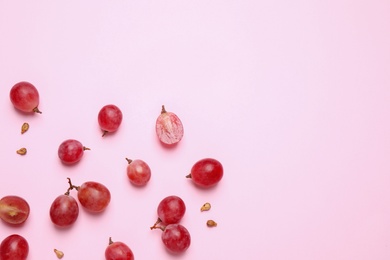 Photo of Flat lay composition with fresh ripe grapes and seeds on pink background. Space for text