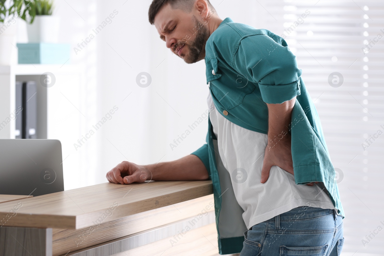 Photo of Man suffering from back pain in office. Bad posture problem